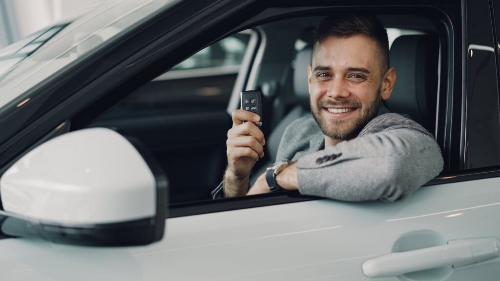 pexels-photo-36729874 Happy young man holding car keys inside a vehicle. Perfect image for car rental or sales.
