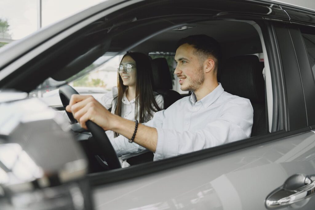 pexels-photo-4895405 A young couple smiling while driving together in a modern car interior.