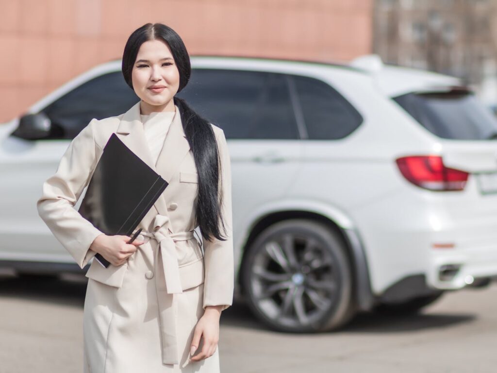 pexels-photo-7736045 Smiling professional woman standing confidently by a luxury car, embodying success.